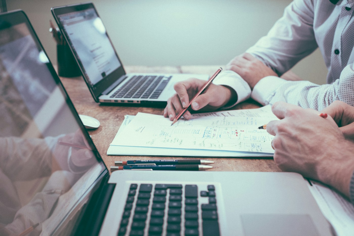 Professionals reviewing documents and data beside laptops